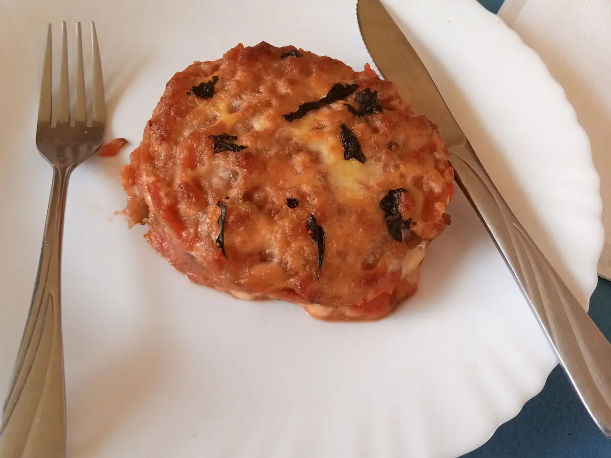 Verdura gratinada con queso y tomate en un plato blanco