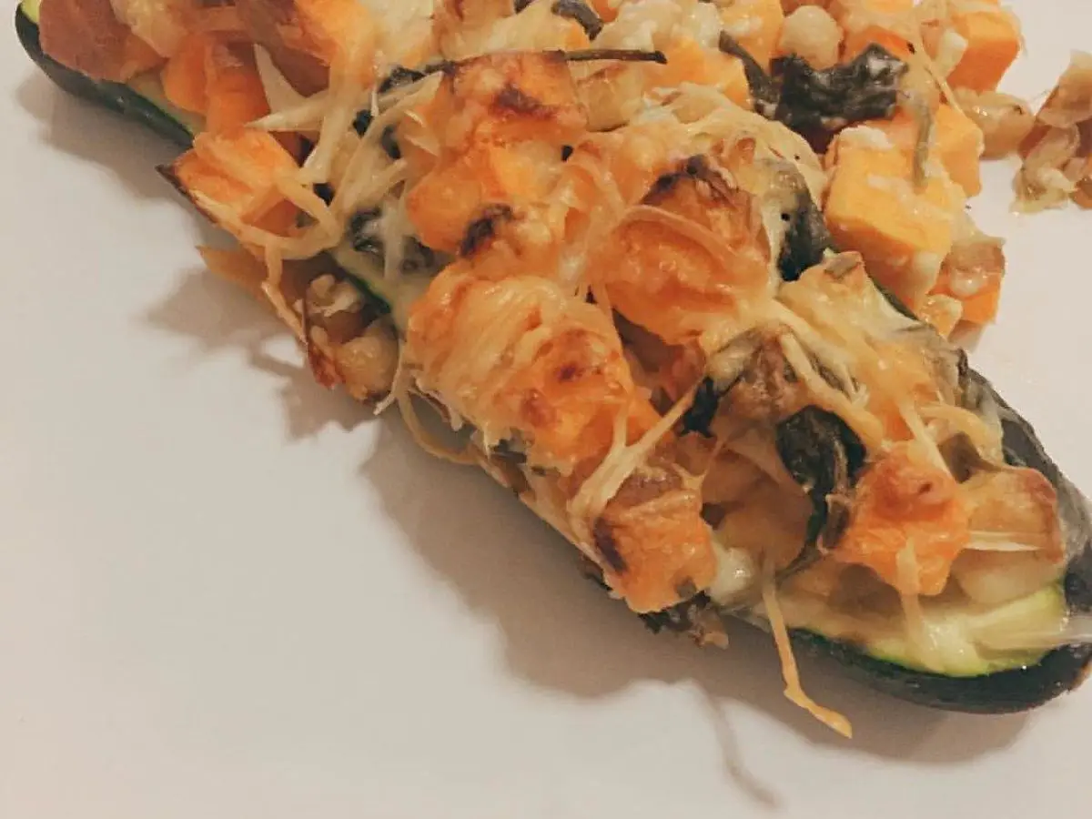 Calabacín abierto por la mitad y relleno de verduras y garbanzos gratinado con queso