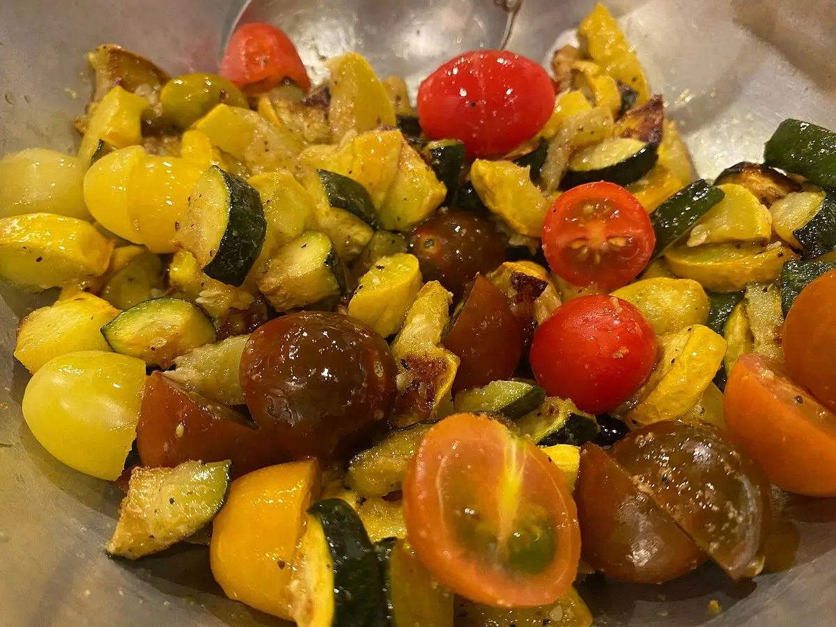 Calabacín y calabaza amarilla salteados con tomates cherry en una fuente metálica