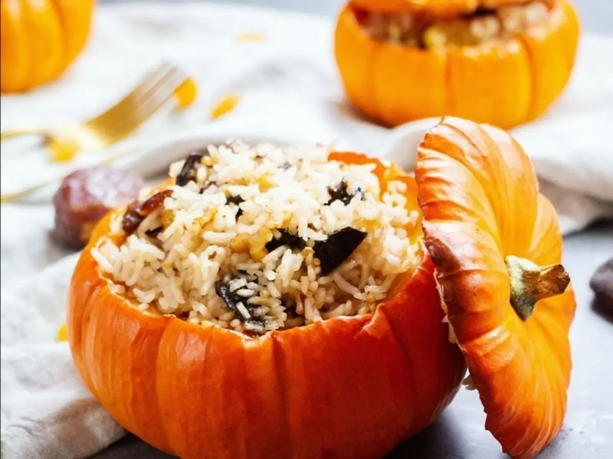 Calabaza naranja pequeña rellena de arroz con frutos secos y su tapa al lado