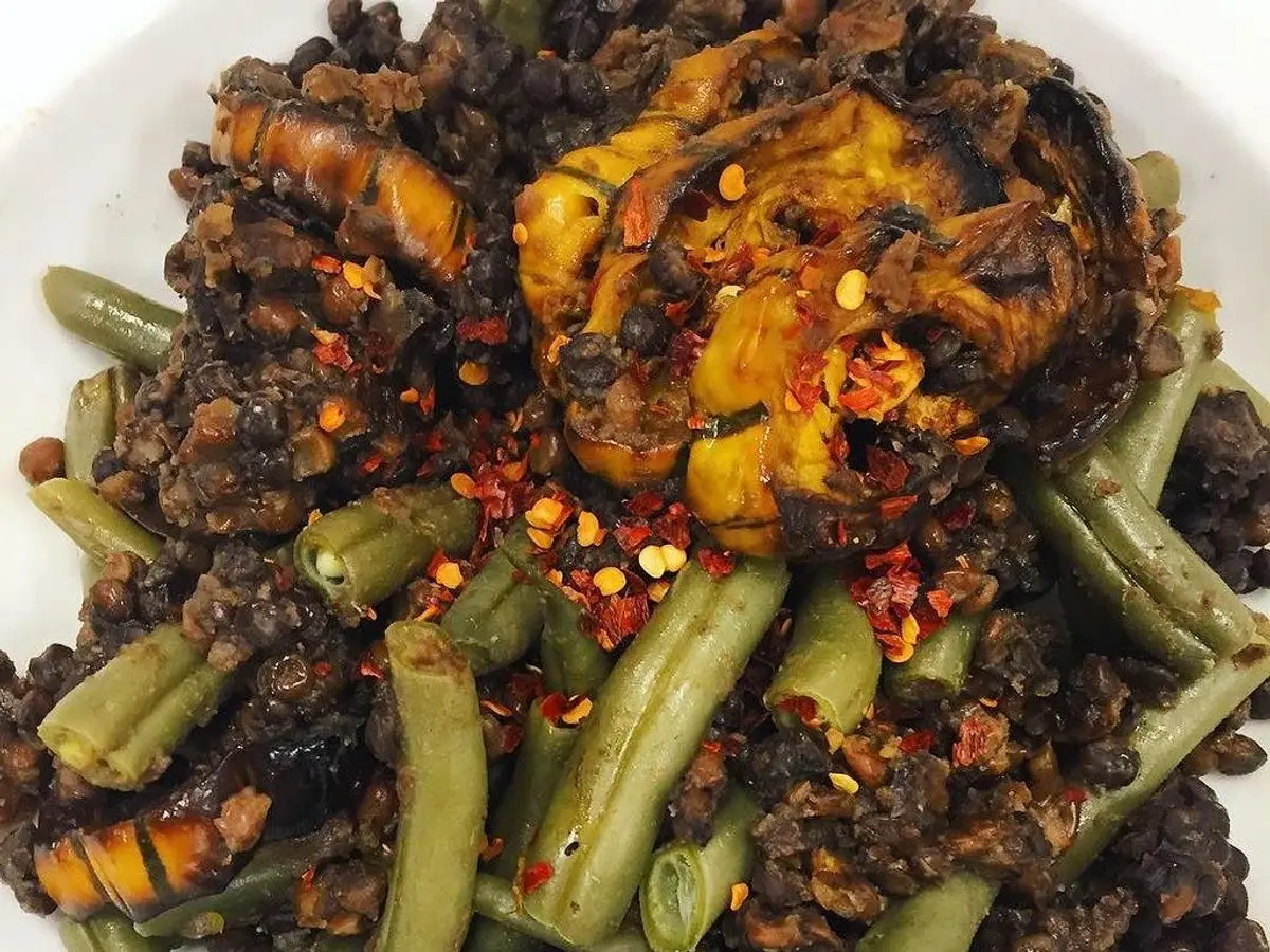 Calabaza asada con judías verdes y lentejas aliñadas con guindilla en un plato