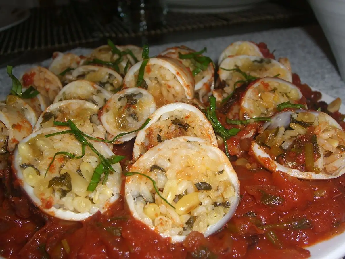 Calamares rellenos al horno en rodajas sobre salsa de tomate espesa con hierbas