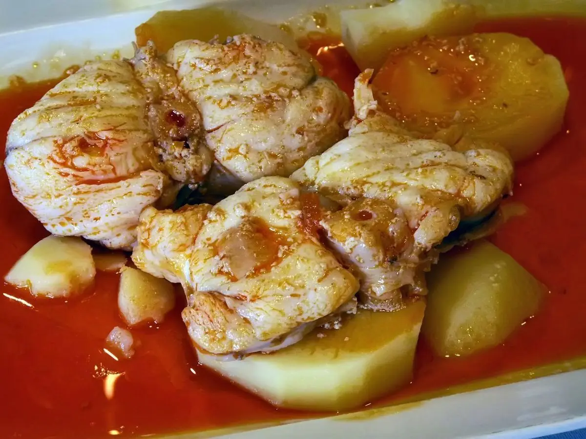 Plato de trozos de pescado blanco con patatas cocidas bañados en salsa de pimentón y aceite
