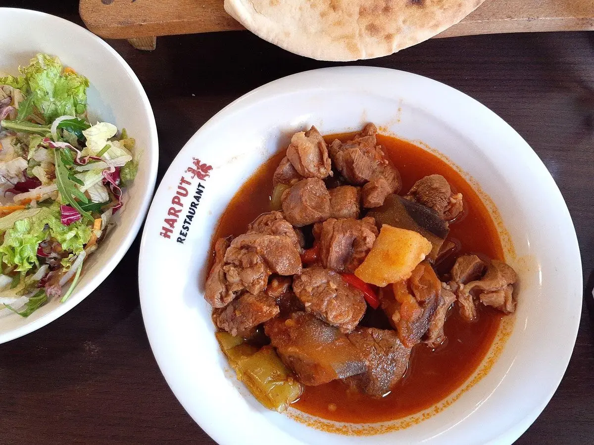 Plato blanco con trozos de carne guisada en salsa roja con patata