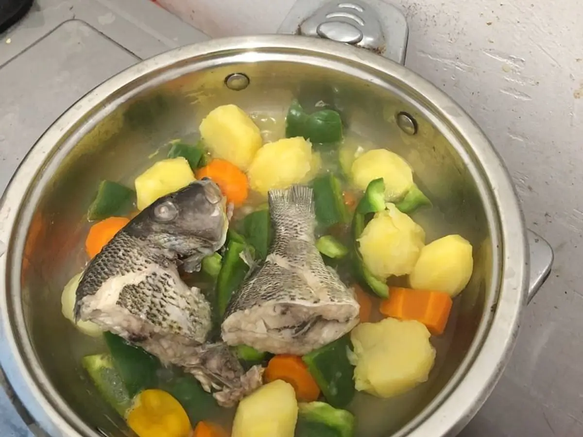 Cazo de caldo de pescado con trozos de pescado, patatas, zanahoria y pimiento verde
