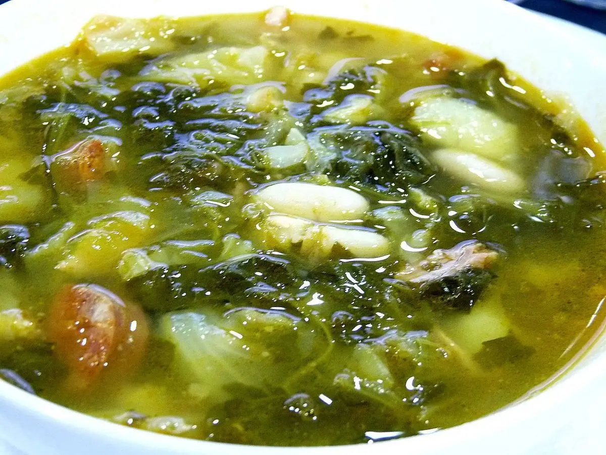 Cuenco de caldo verde con berza, alubias blancas y trozos de carne