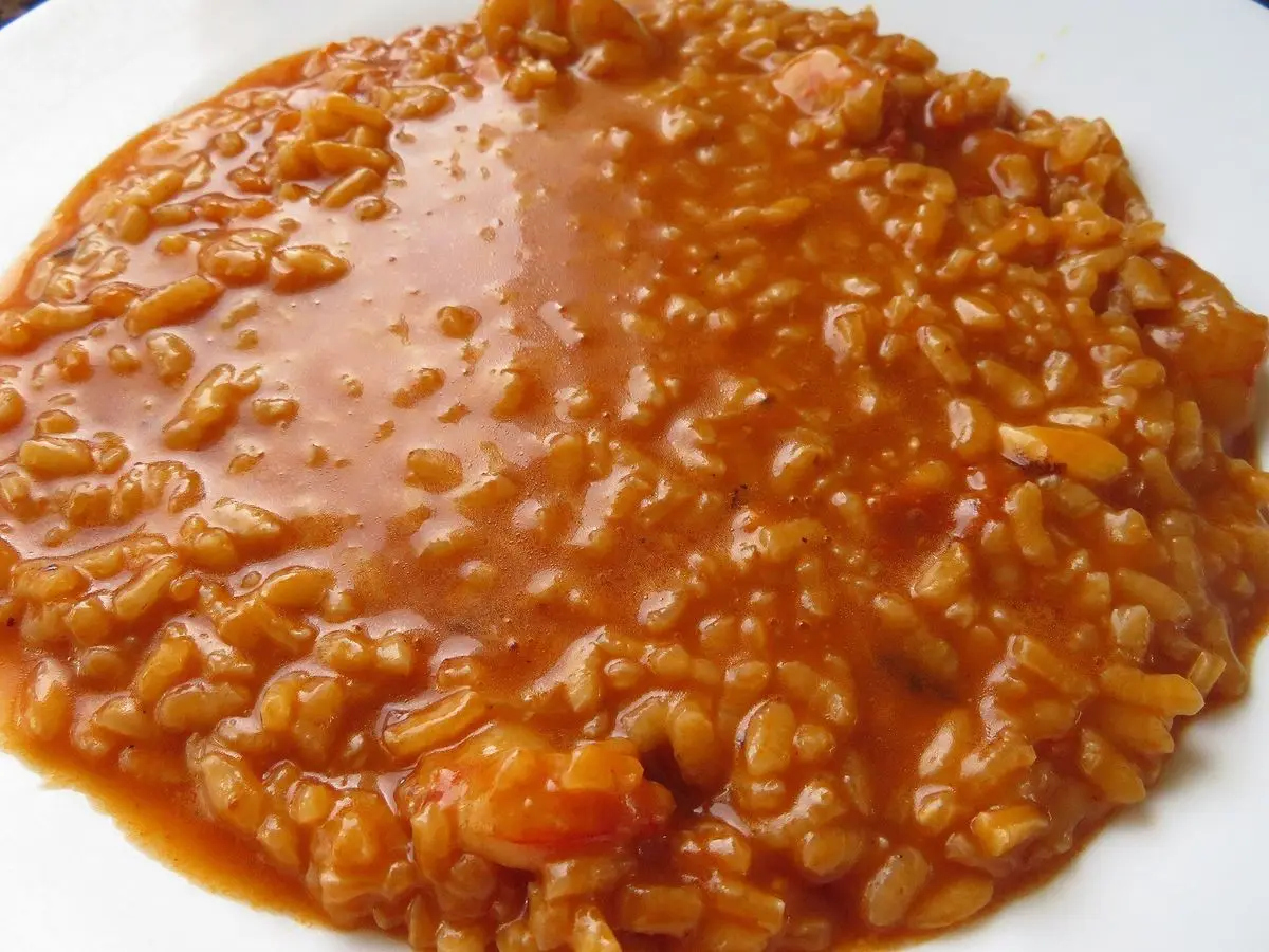 Plato de arroz caldoso de pescado en un caldo rojizo de ñora y pimentón