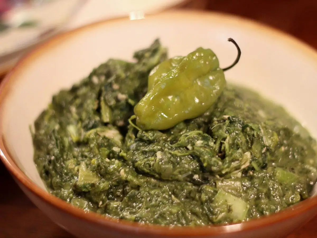 Cuenco de callaloo, guiso espeso de verduras de hoja verdes, con un chile habanero encima