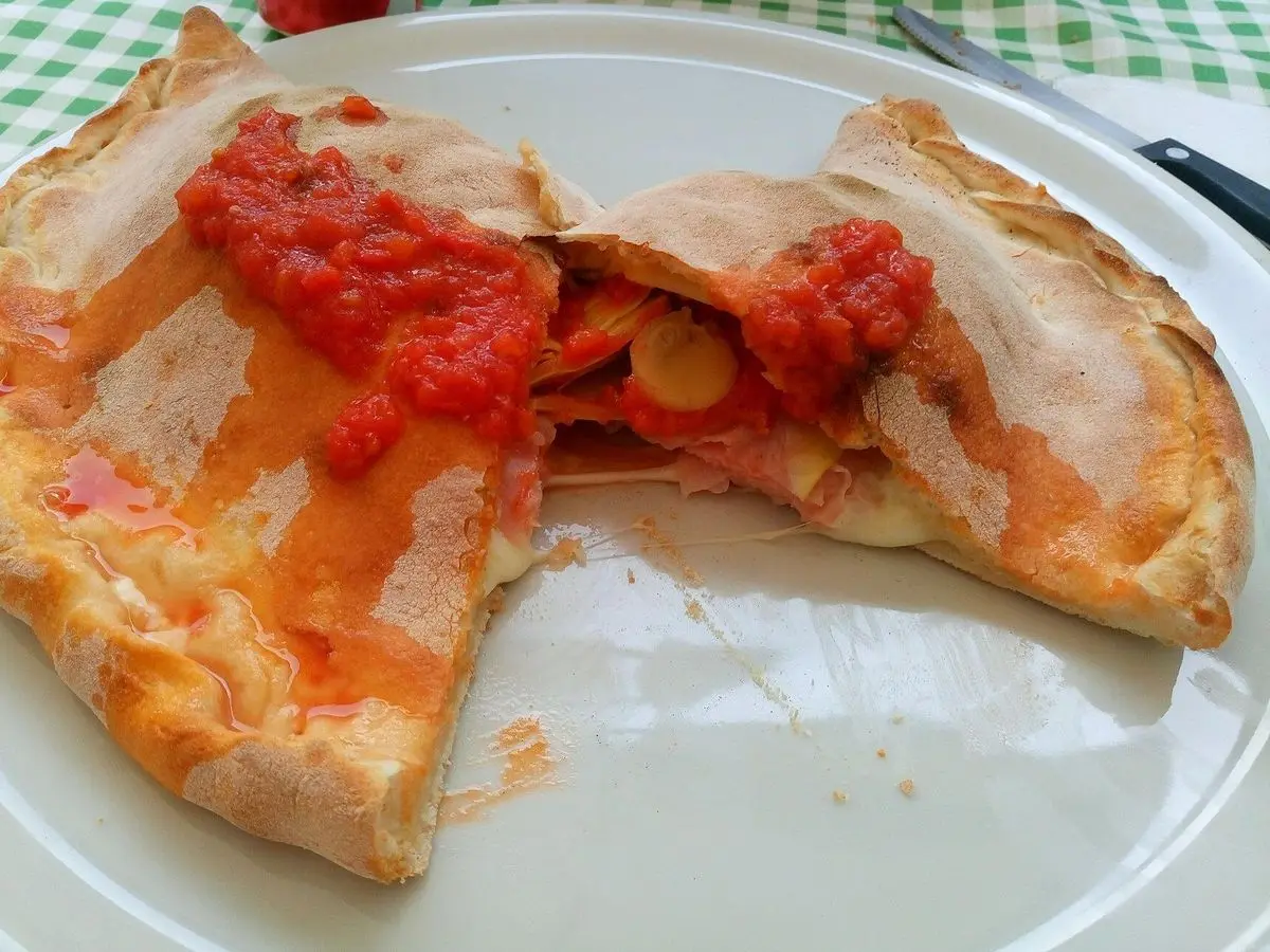 Calzone abierto relleno con salsa de tomate sobre un plato blanco