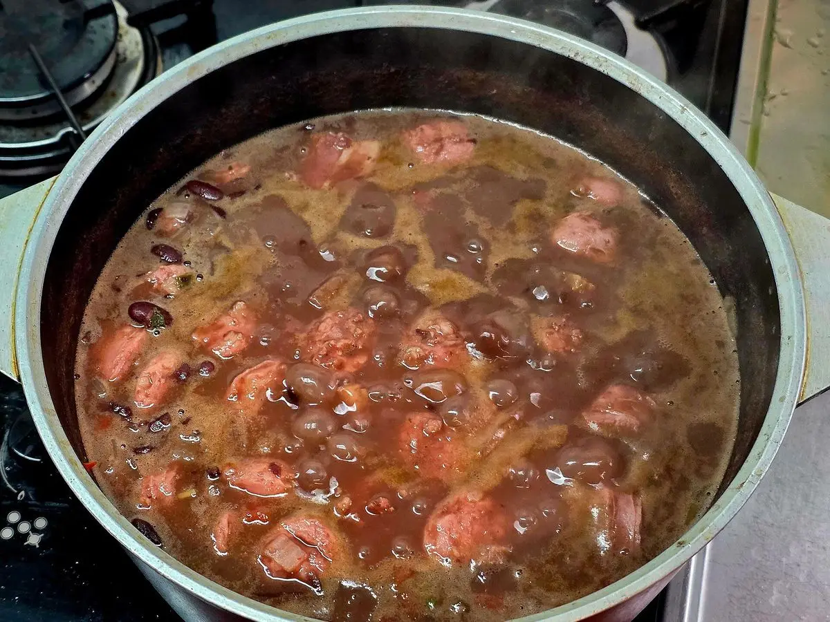 Olla con guiso espeso de alubias rojas con rodajas de chorizo y trozos de panceta