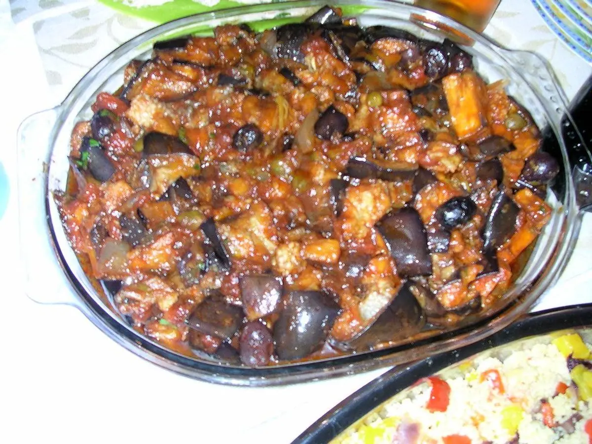 Fuente de cristal llena de caponata de berenjena guisada con tomate