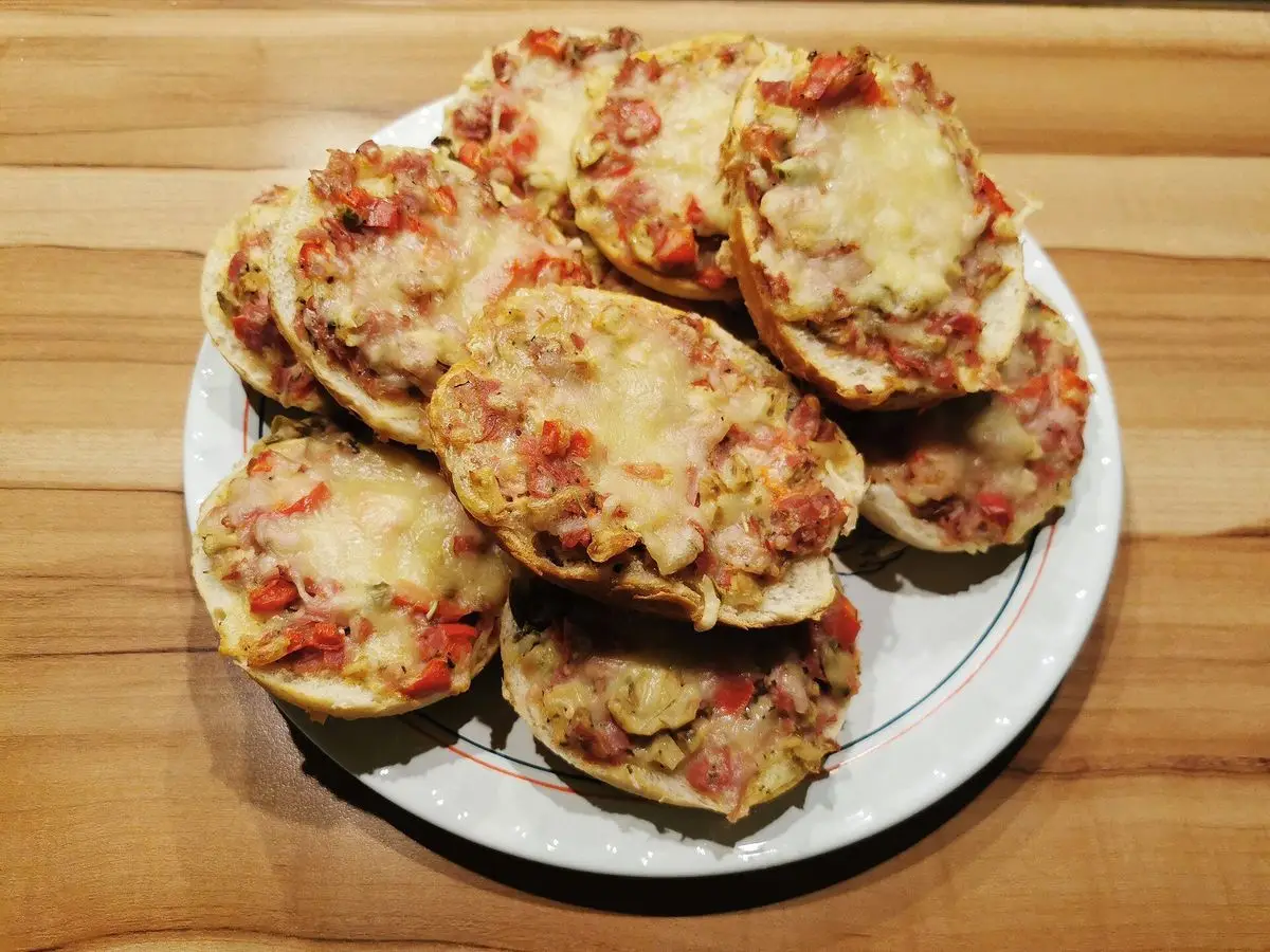 Montoncito de mini pizzas redondas con tomate y queso gratinado sobre un plato