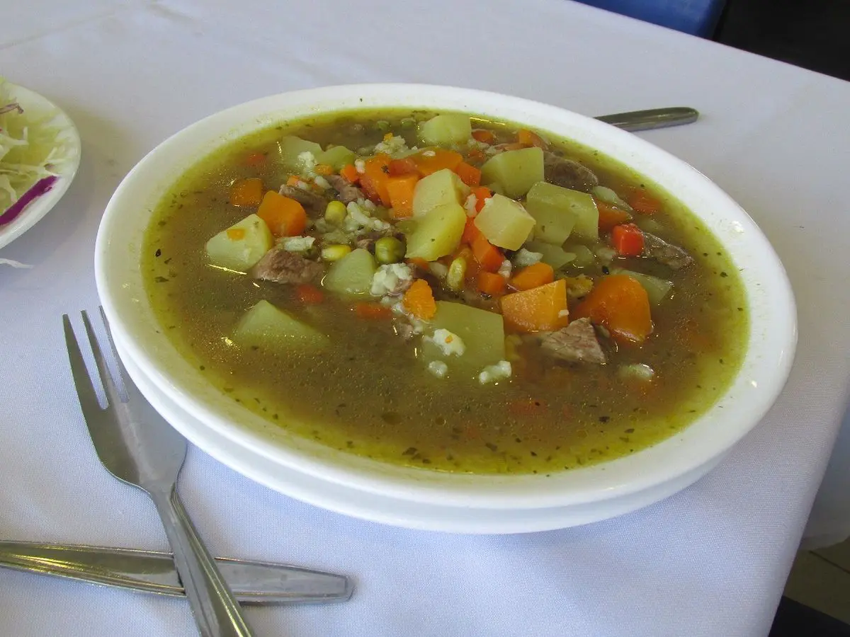 Plato hondo de guiso de carbonada con calabaza, zanahoria, patata y granos de maíz en caldo