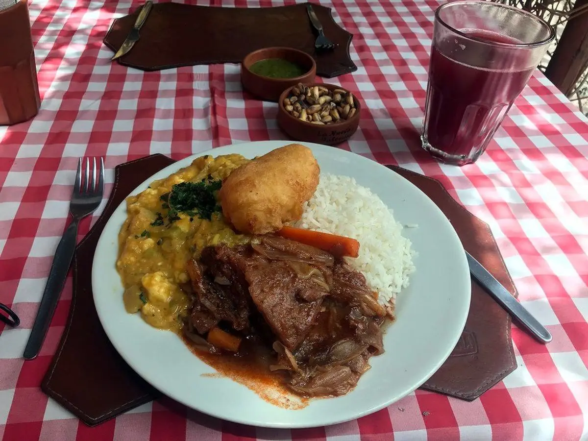 Plato con guiso de ternera, calabaza y arroz blanco sobre mantel de cuadros rojos