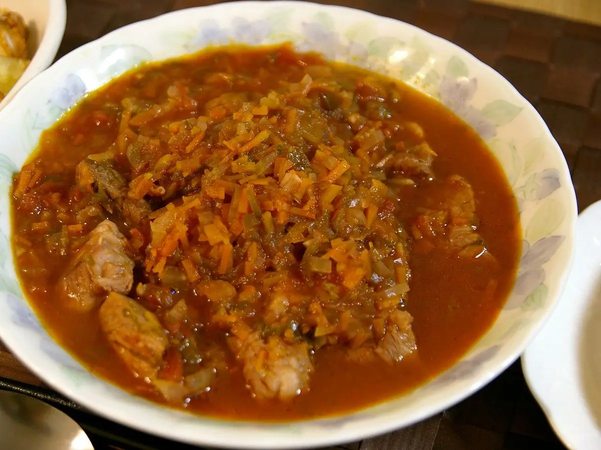 Plato hondo con guiso de carne en salsa de tomate y pimiento