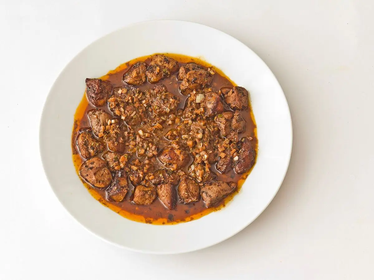 Plato blanco con carne fiesta: tacos de cerdo fritos en su adobo rojo de pimentón y ajo