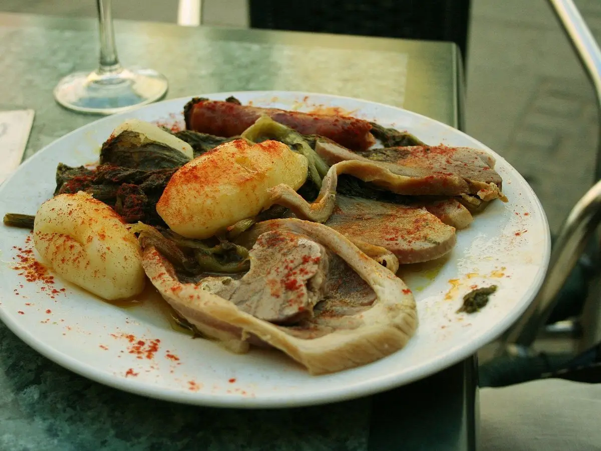 Plato de carne cocida con patatas espolvoreadas de pimentón y grelos verdes