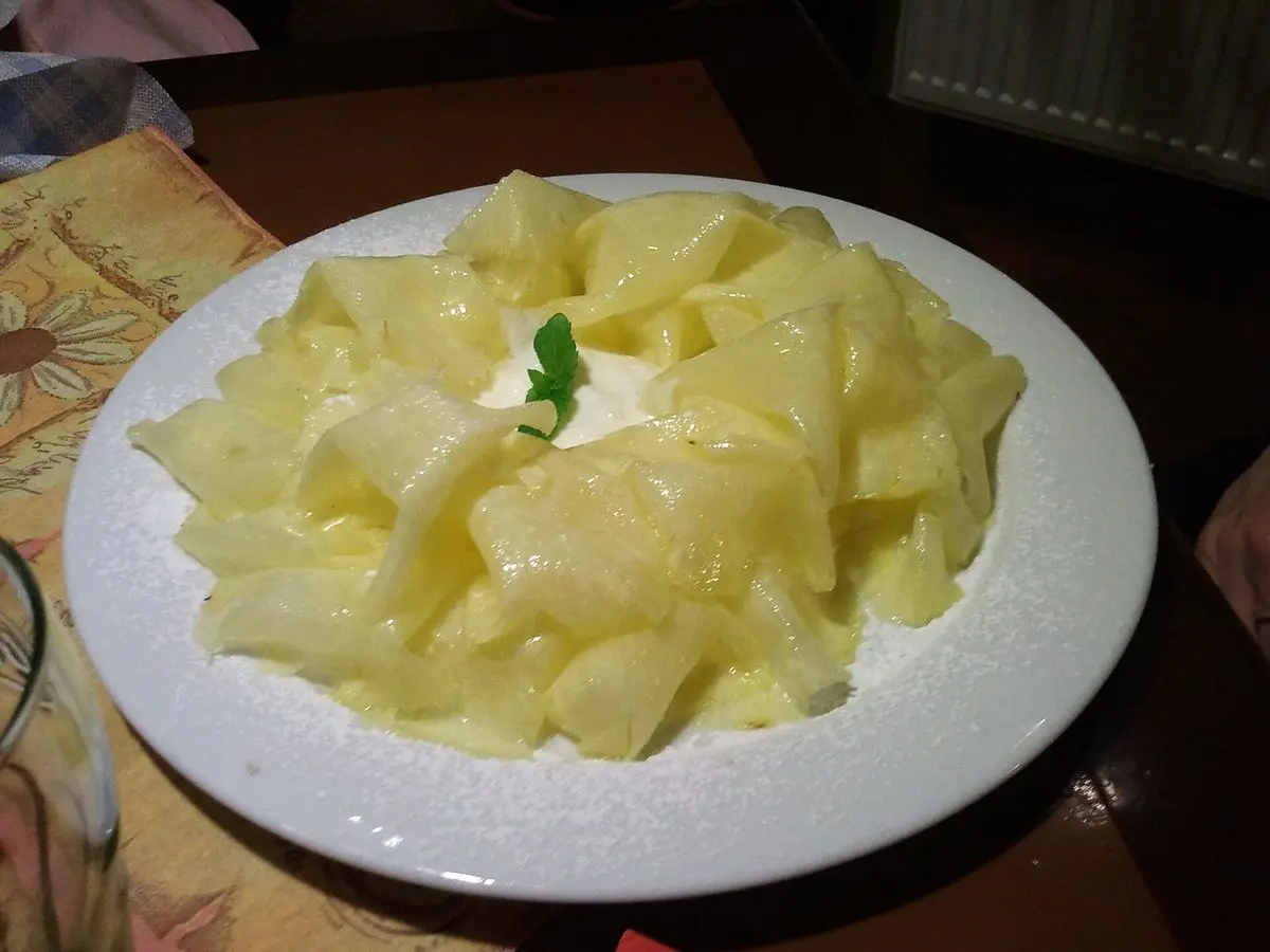 Plato blanco con láminas finas de piña dispuestas en círculo y una hojita de menta