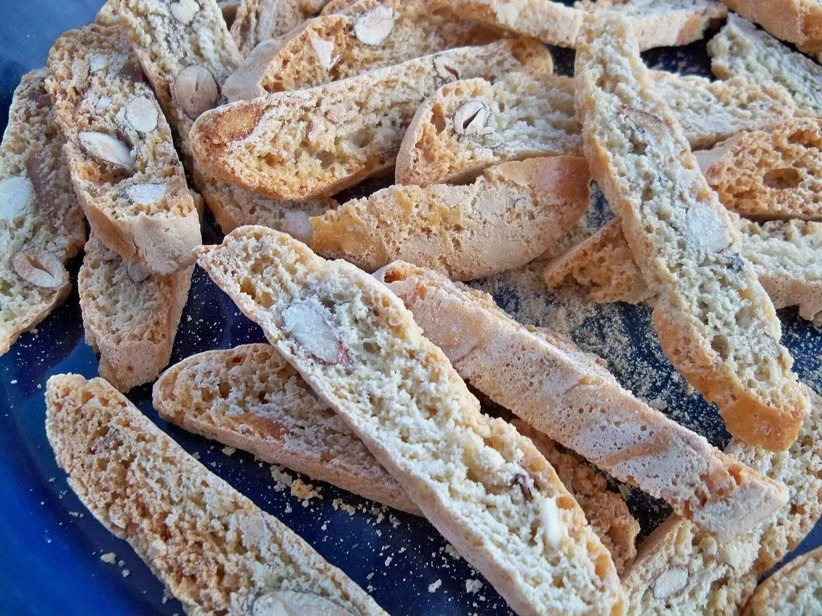 Montón de galletas crujientes alargadas con almendras sobre una fuente azul