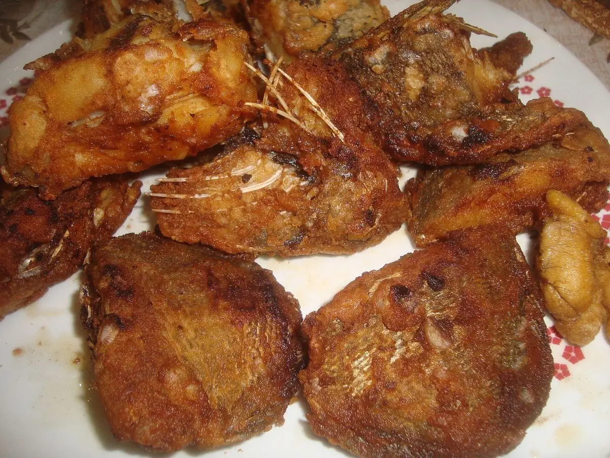 Trozos de pescado adobado, rebozado y frito, dorados y crujientes, servidos en un plato blanco