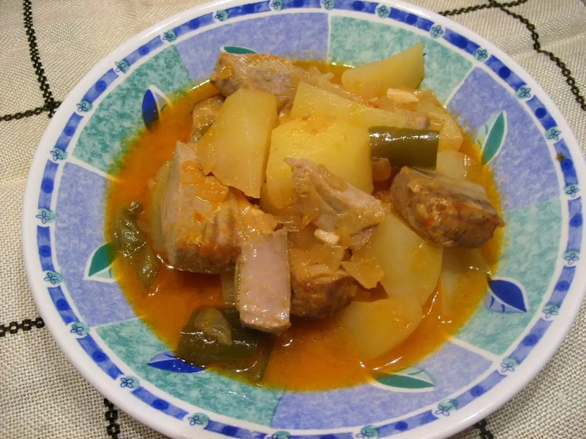 Plato de guiso de pescado con patatas en dados y pimiento en salsa anaranjada