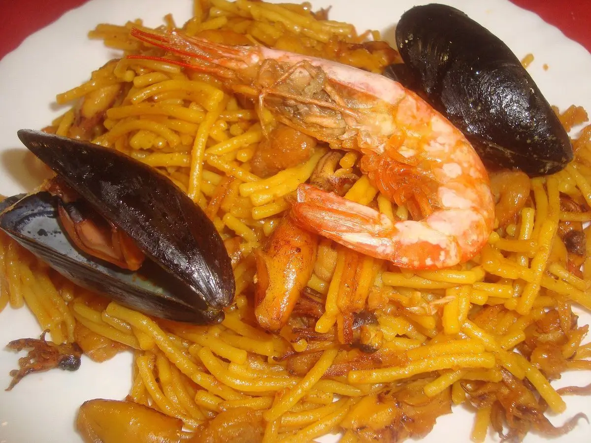 Plato de fideuá con fideos dorados, gamba y mejillones