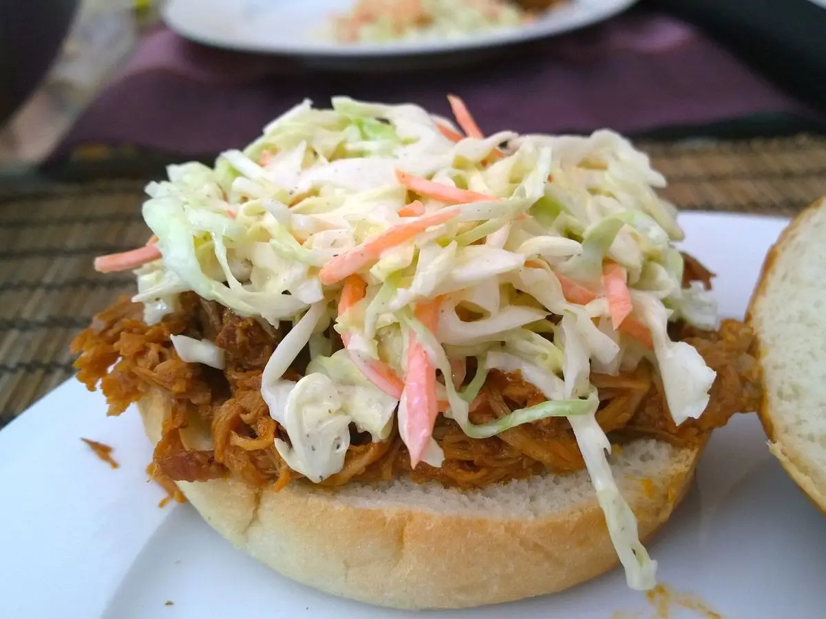 Bocadillo de cerdo desmechado con ensalada de col fresca sobre un pan de hamburguesa