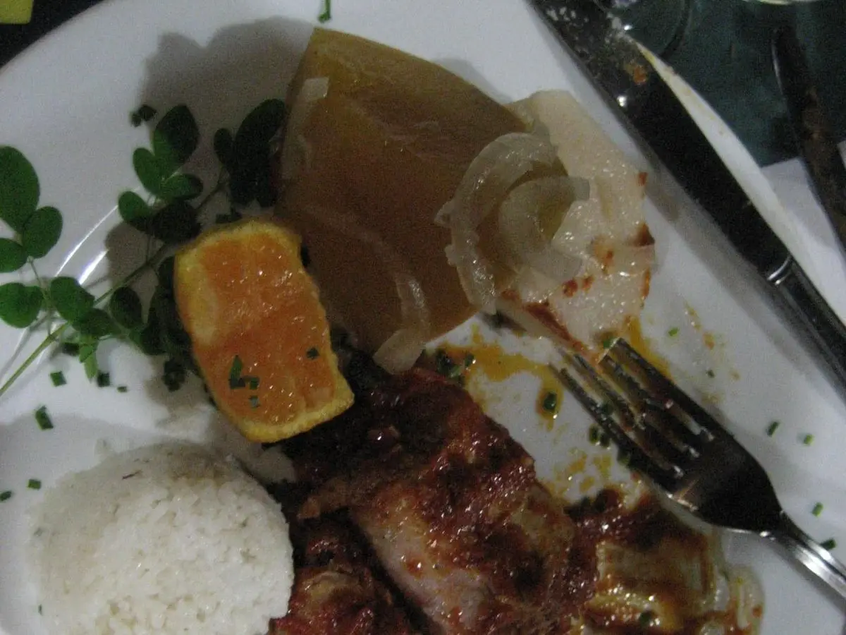 Cerdo asado con arroz blanco y rodaja de naranja en un plato