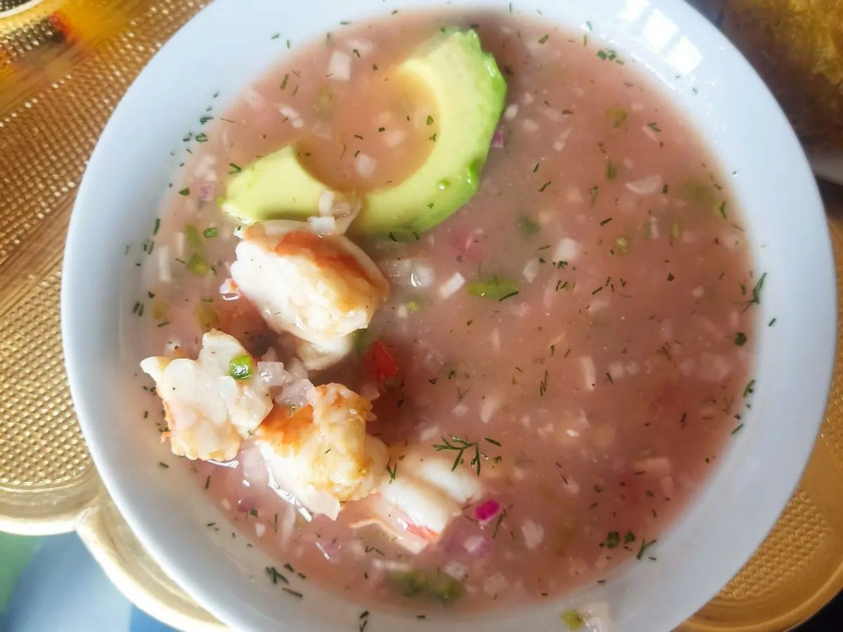 Ceviche de camarón en caldo rosado con aguacate en un plato hondo blanco