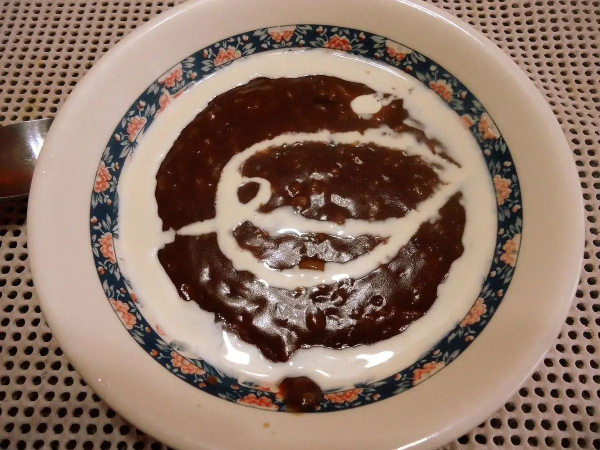 Plato hondo de gachas de arroz con cacao con un remolino de leche blanca por encima