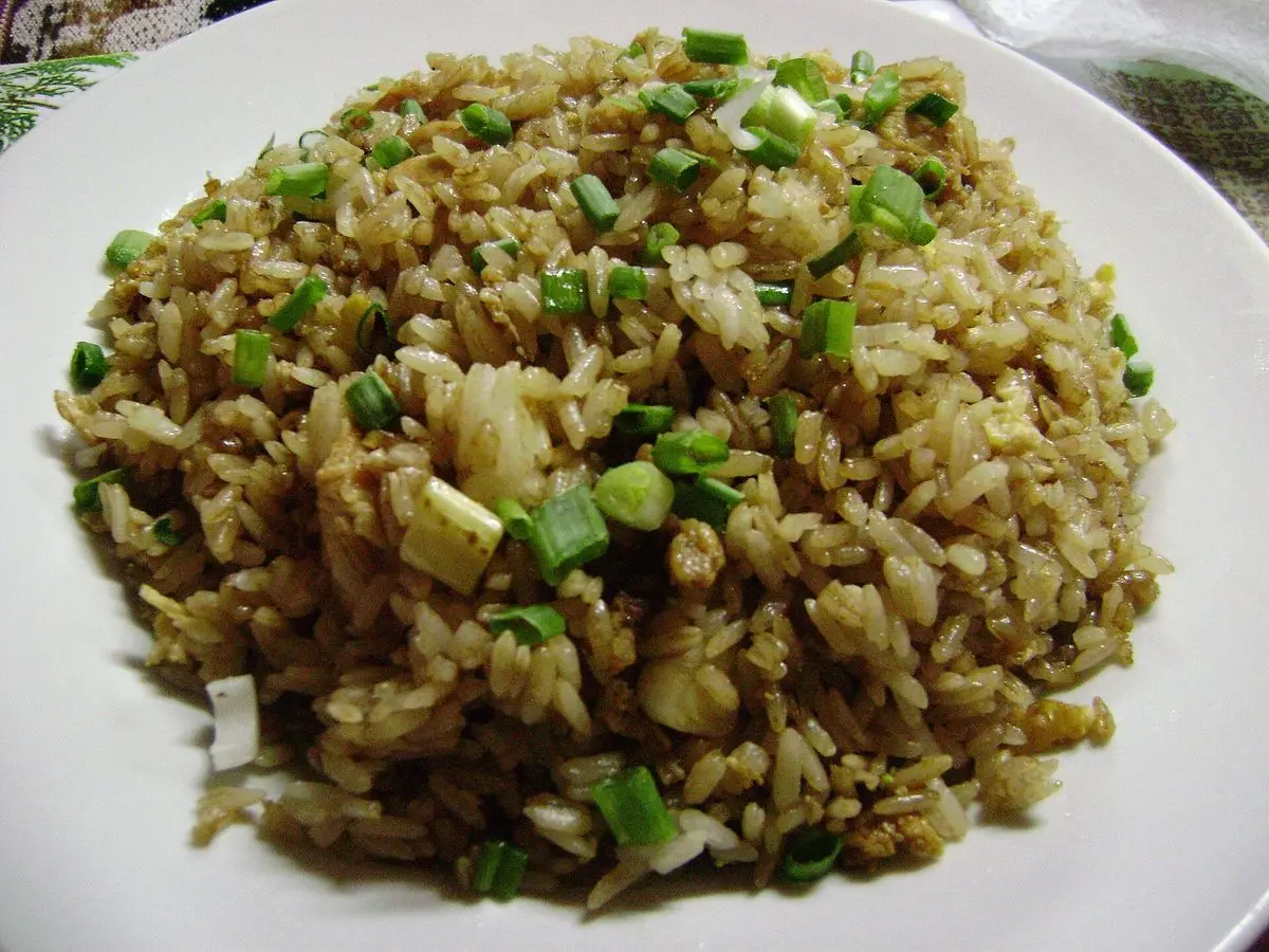Plato blanco de arroz chaufa salteado con cebolleta picada y huevo revuelto