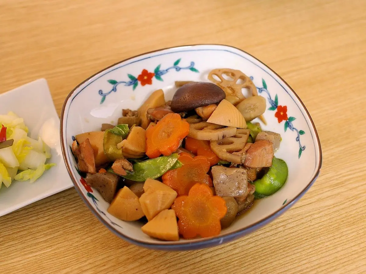 Cuenco de guiso japonés de pollo con zanahoria, raíces, setas y guisantes