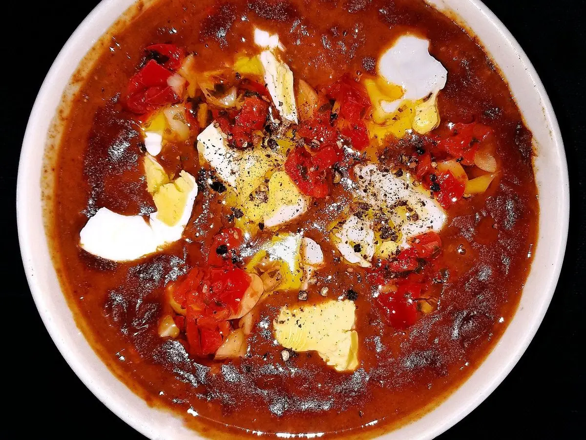 Cuenco blanco de chili con carne, alubias y pimiento rojo, con crema y queso por encima