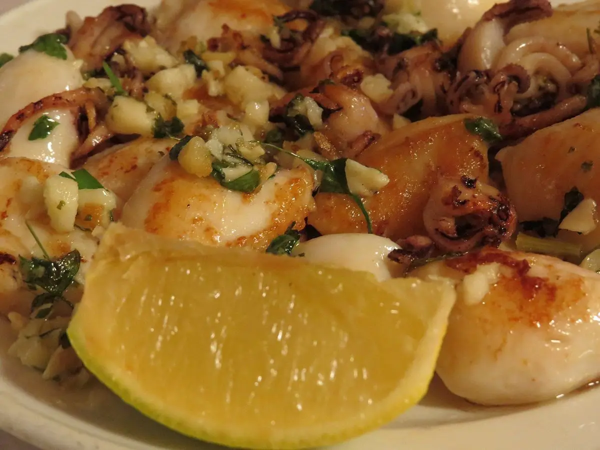 Chipirones a la plancha con ajo picado y perejil, acompañados de una cuña de limón