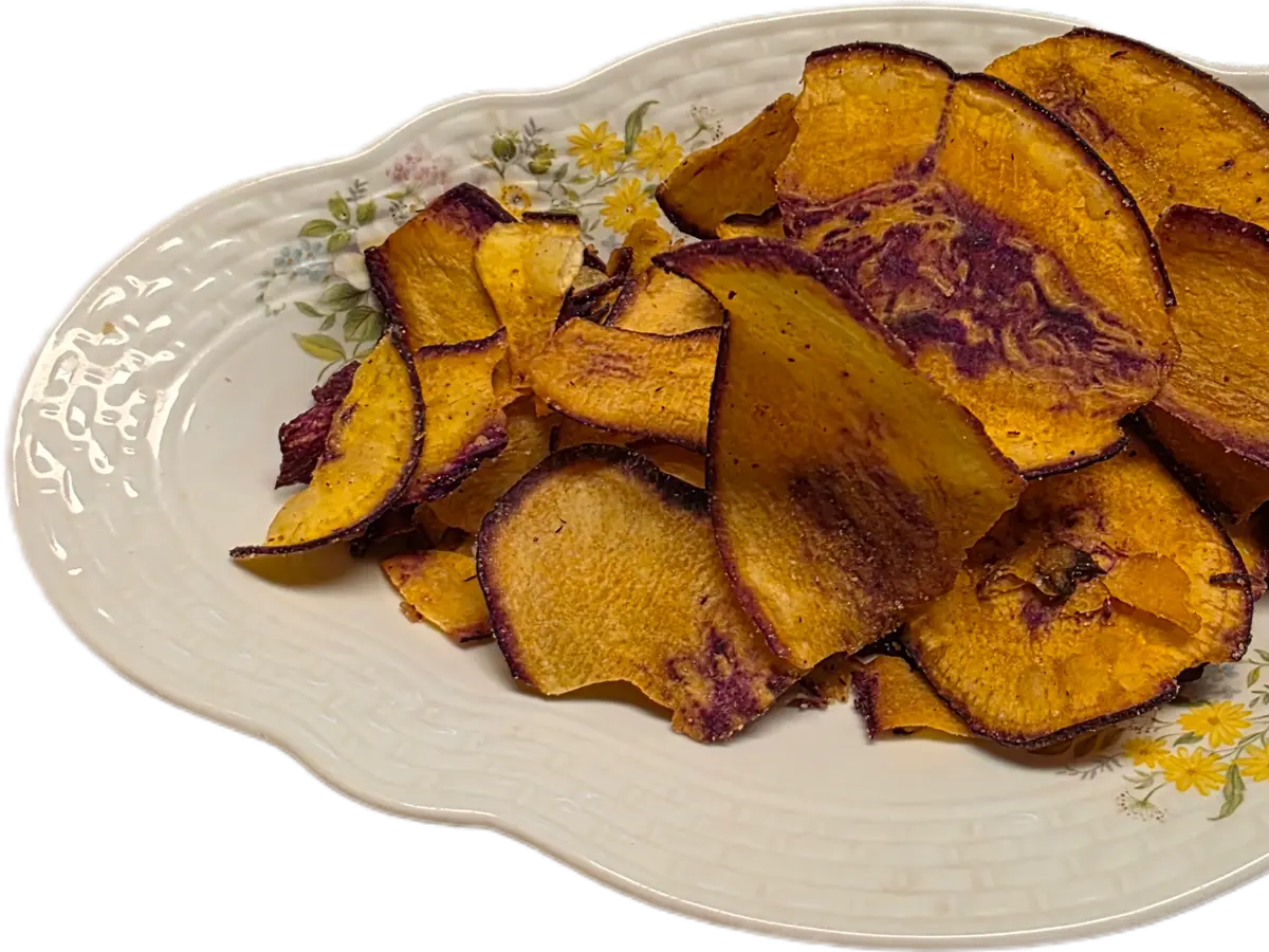Chips de boniato de color anaranjado y violeta en un plato decorado con flores