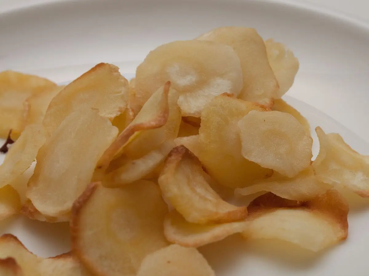 Montón de chips crujientes de chirivía sobre un plato blanco