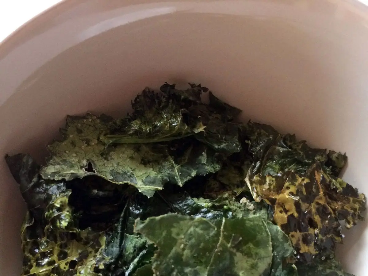 Chips de kale crujientes de color verde oscuro en un cuenco blanco