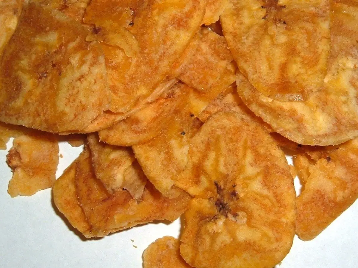 Montón de chips de plátano fritos de color dorado anaranjado sobre fondo blanco