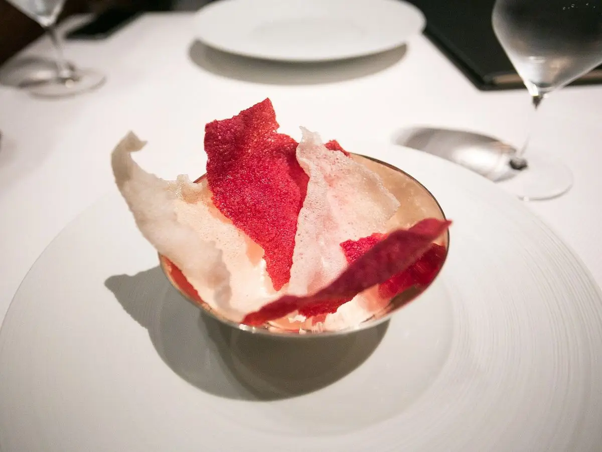 Cuenco con finas chips crujientes de remolacha de color rojo intenso sobre un plato blanco