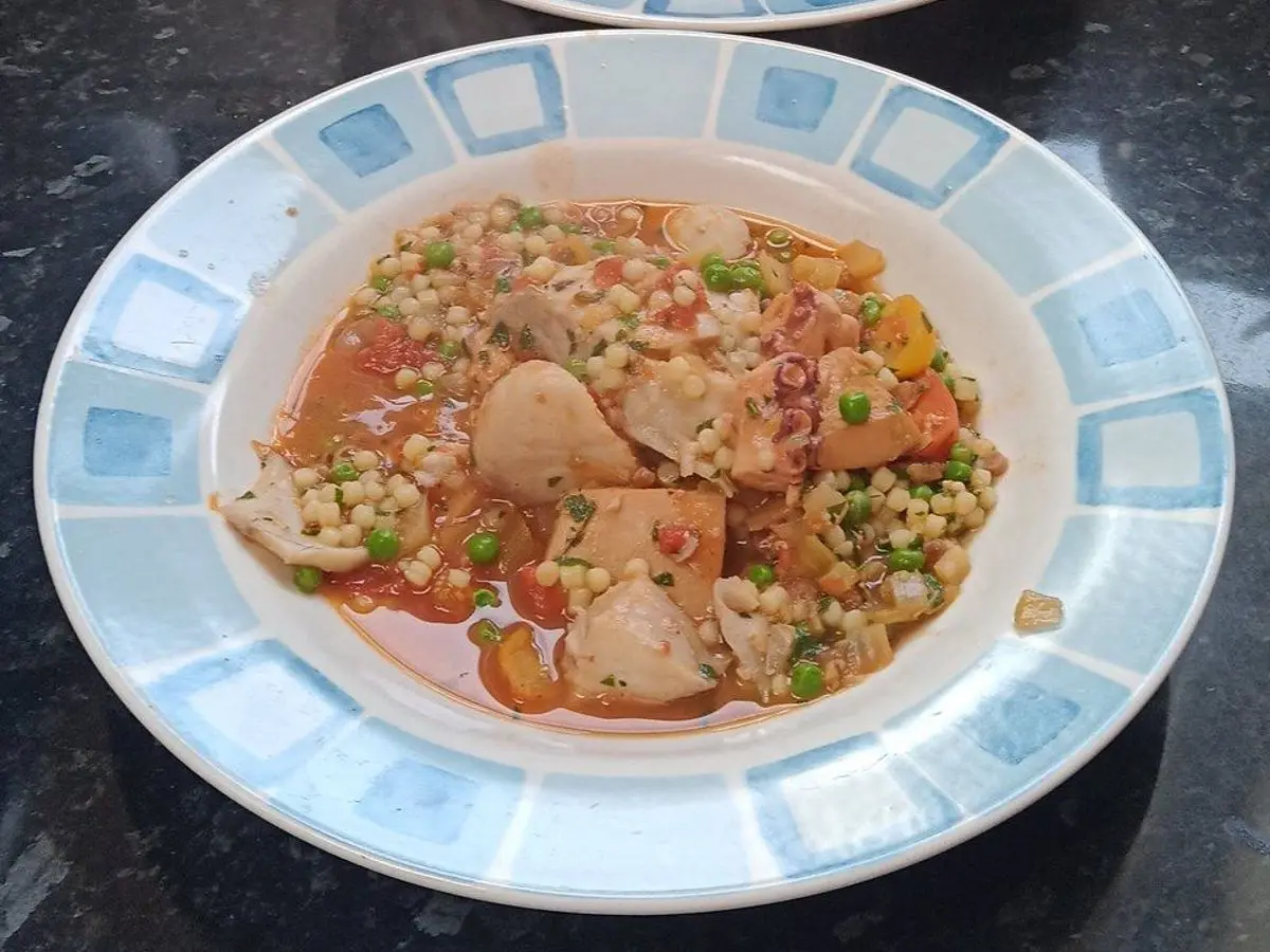 Platos hondos con guiso de sepia en salsa de tomate con verduras y pasta menuda