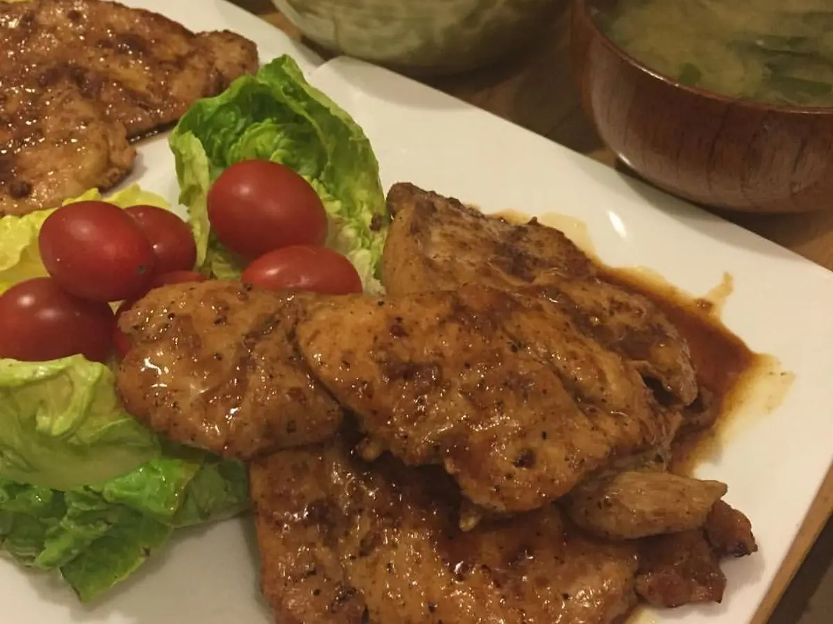 Chuletas de cerdo doradas con lechuga, tomates cherry y calabaza guisada en un plato