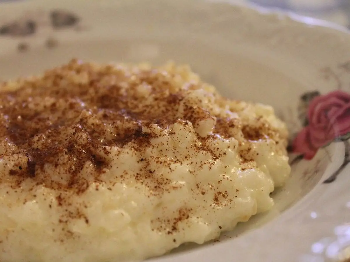 Plato de gachas cremosas de arroz con leche espolvoreadas con canela por encima