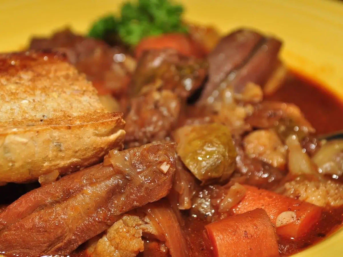 Primer plano de guiso de carne dorada con zanahoria y pimiento