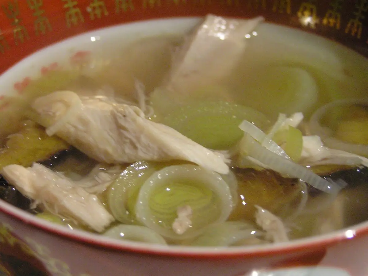 Cuenco de sopa clara con tiras de pollo y aros de puerro en caldo