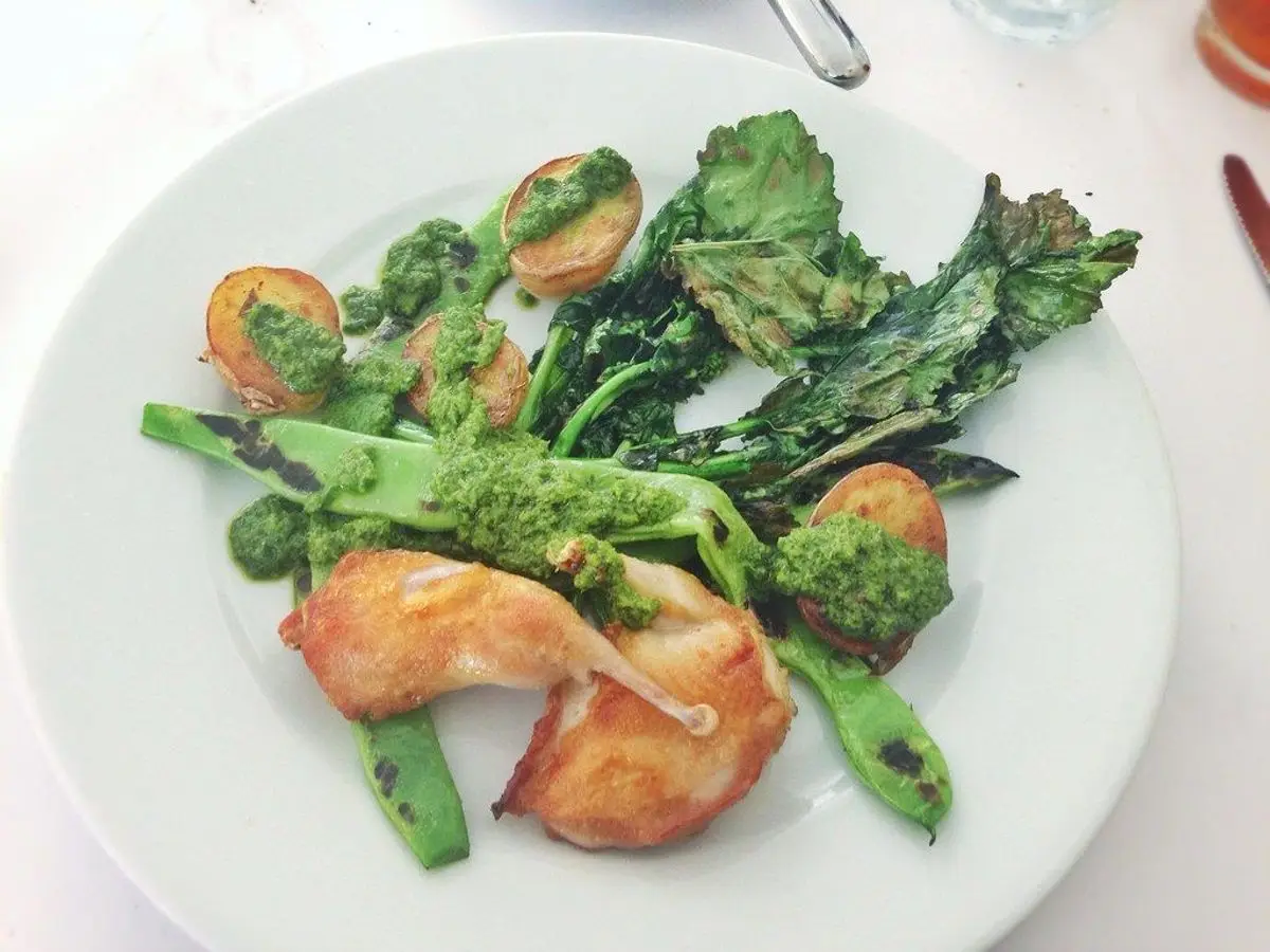 Codornices asadas con patatas pequeñas, col rizada y judías verdes en un plato blanco