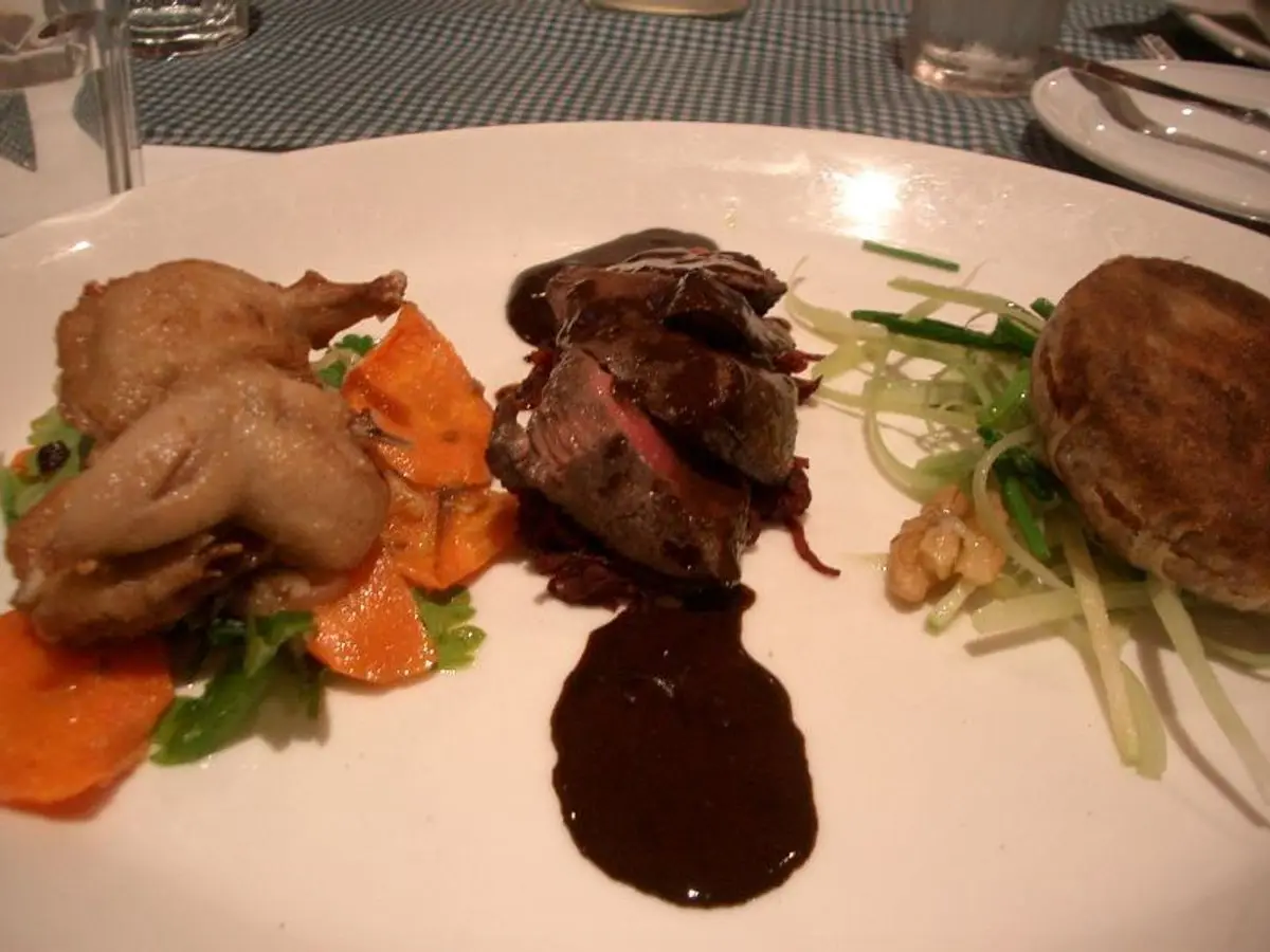 Codorniz asada con verduras y salsa oscura en un plato blanco