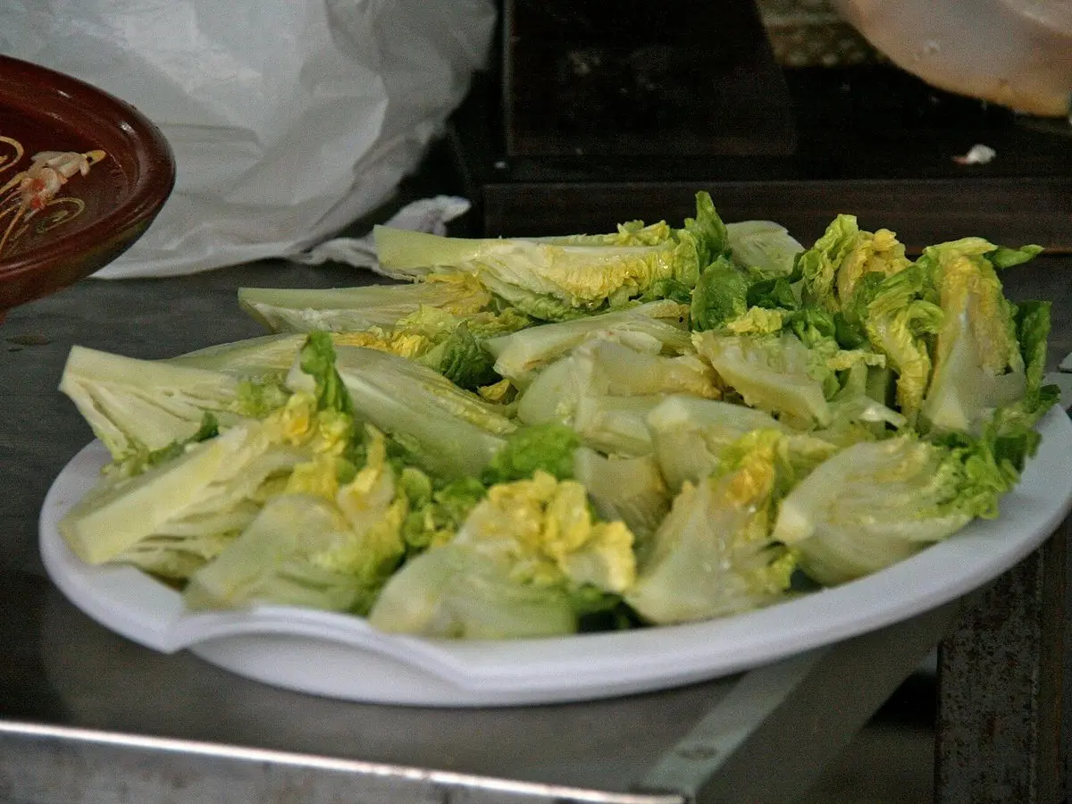 Cogollos de lechuga tiernos y abiertos servidos en una fuente blanca