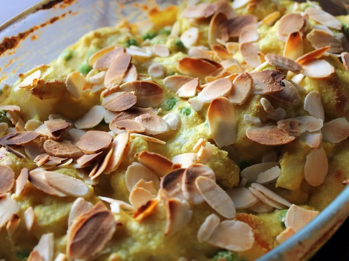 Coliflor gratinada con salsa cremosa y láminas de almendra tostadas, en una fuente de cristal