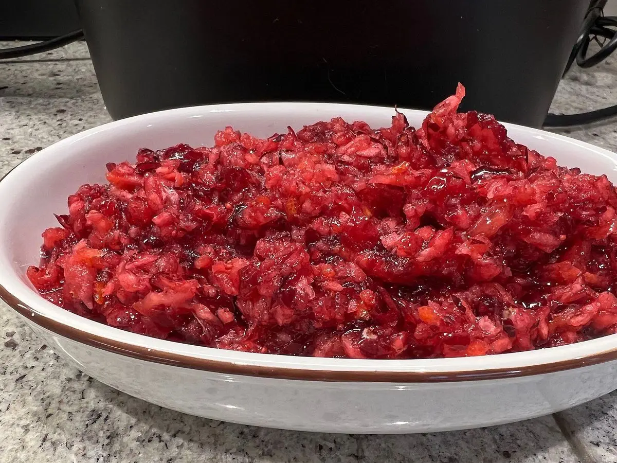 Fuente blanca llena de compota de arándanos rojos troceados y naranja