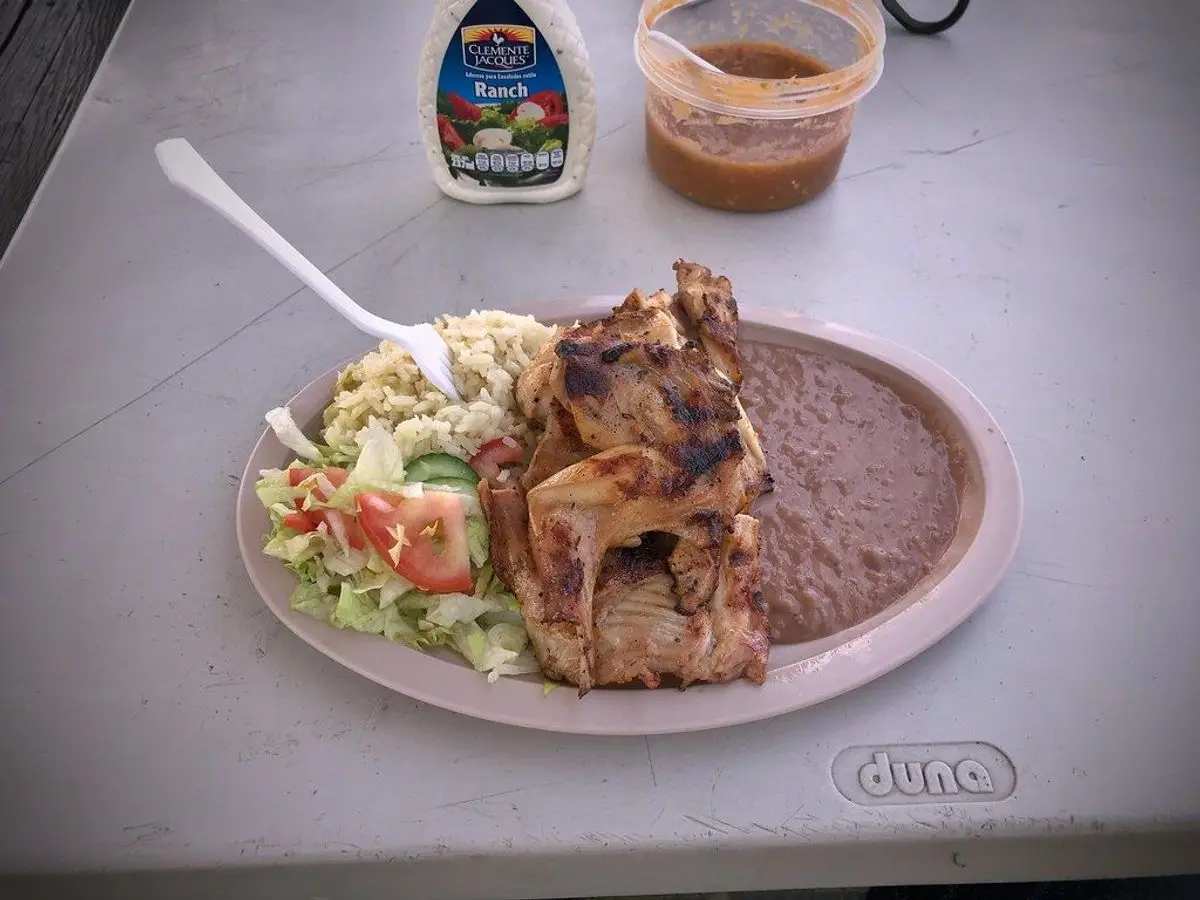 Conejo a la plancha dorado con ensalada de tomate y lechuga en un plato ovalado